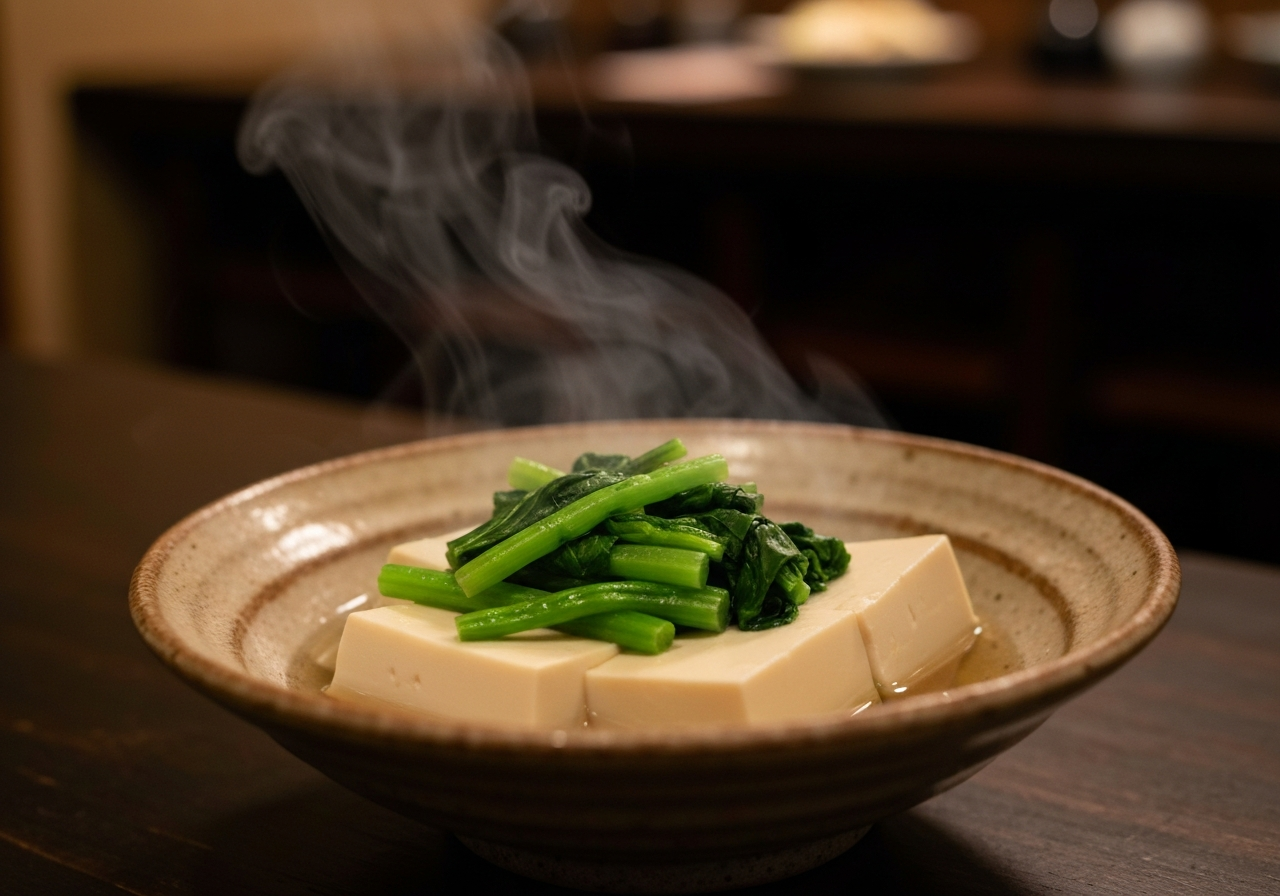 A close-up, slightly blurry shot taken with a smartphone of a steaming bowl of yudofu (hot tofu) with vibrant green seasonal vegetables in a simple, rustic ceramic dish. The background is softly out of focus, suggesting a cozy, dimly lit family-run restaurant in Kyoto. The lighting is warm and natural, as if captured in a spontaneous moment